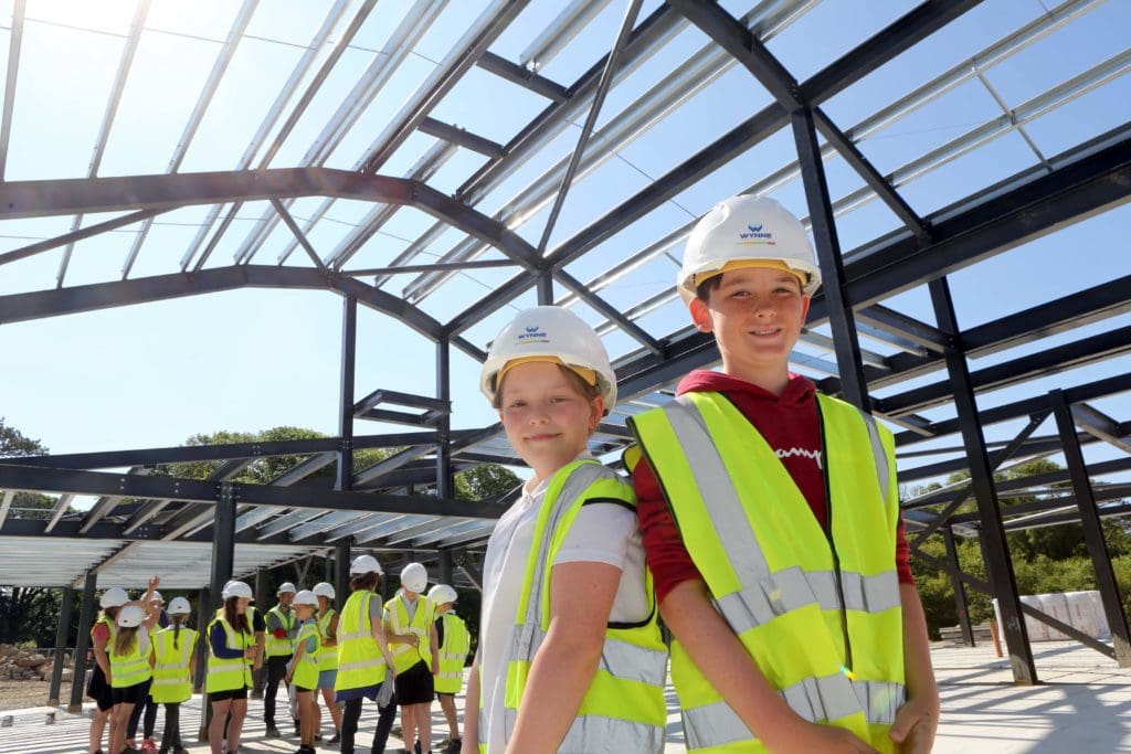Pupils write names onto the structure of new Ysgol Treferthyr in Criccieth