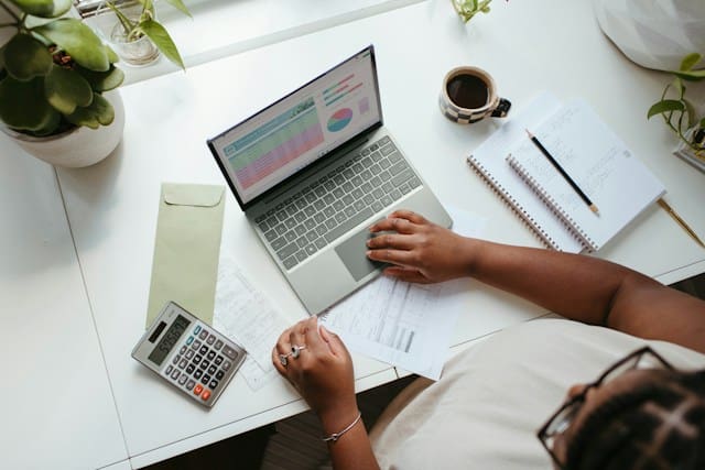 A small business owner planning at a desk with a laptop and notes